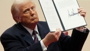 US-Präsident Trump präsentiert stolz seine Unterschrift.