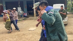 Ein verletzter kambodschanischer Mann (2. von rechts) wird von zwei Personen getragen.