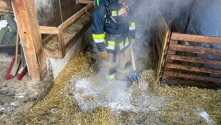 Ein Feuerwehrmann auf dem noch rauchenden Stroh