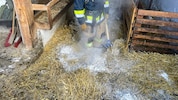 Ein Feuerwehrmann auf dem noch rauchenden Stroh