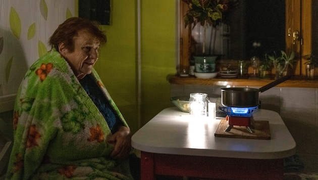 Während eines Blackouts kocht eine Bewohnerin von Kiew ihr Essen auf einem Gaskocher. Ständige ...