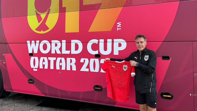 Trainer Hermann Stadler vor dem Teambus und mit den Unterschriften seiner Youngsters.