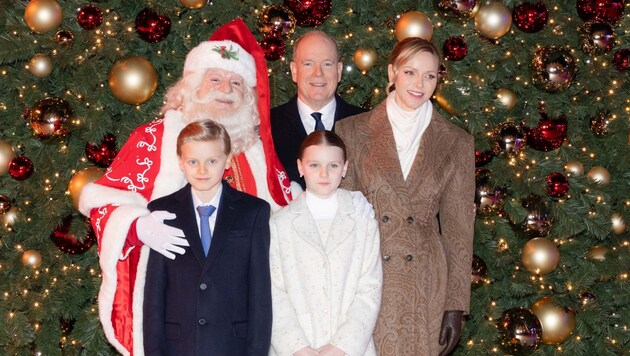 Die Fürstenfamilie posiert mit dem Weihnachtsmann vor dem beleuchteten Weihnachtsbaum.