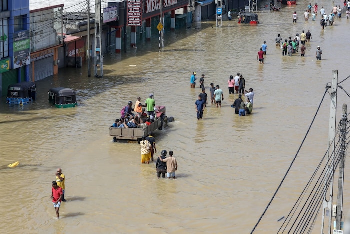 In der Nähe von Colombo waten Menschen durch das Wasser.