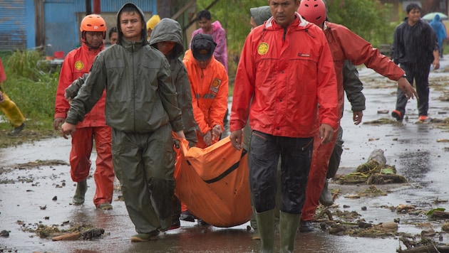 Helfer tragen ein Todesopfer in Indonesien.