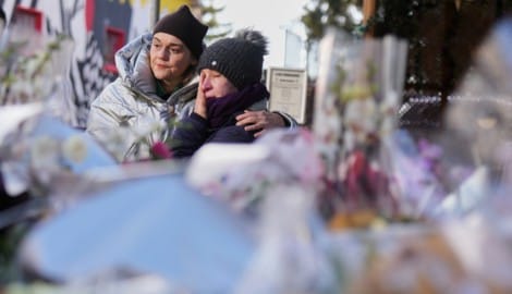 Vor dem ausgebrannten Gebäude legen Menschen still Erinnerungen nieder. Die Trauer ist greifbar.