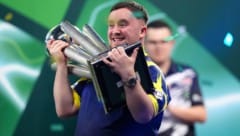 Luke Littler jubelt mit der WM-Trophäe.