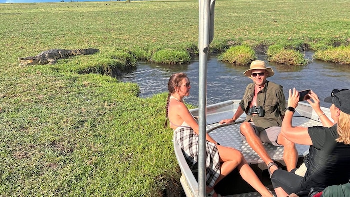 Krokodil mit offenem Maul als Fotokulisse am Flussufer.