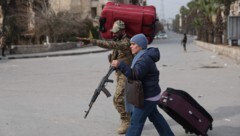 Ein syrischer Soldat hilft einer Zivilistin am 3. Jänner 2026 bei ihrer Flucht in Aleppo