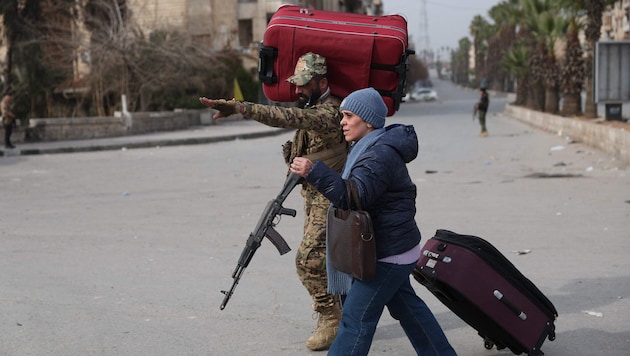 Ein syrischer Soldat hilft einer Zivilistin am 3. Jänner 2026 bei ihrer Flucht in Aleppo