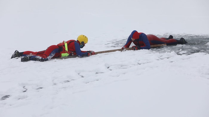 Der Retter nähert sich flach auf dem Eis liegend. Eine herumliegende Latte wird zur ...