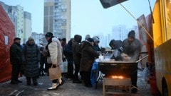 Menschen in Kiew stehen vor einer Essensausgabe an.