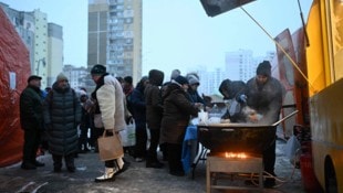 Menschen in Kiew stehen vor einer Essensausgabe an.
