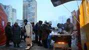 Menschen in Kiew stehen vor einer Essensausgabe an.