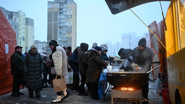 Menschen in Kiew stehen vor einer Essensausgabe an.