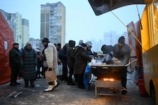 Menschen in Kiew stehen vor einer Essensausgabe an.