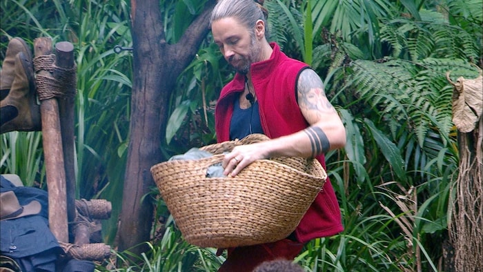 Gil Ofarim bringt einen Korb frischer Handtücher ins Camp und verteilt sie