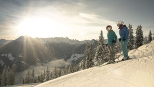 Skifahrer genießen den wunderebaren Ausblick von der Piste.