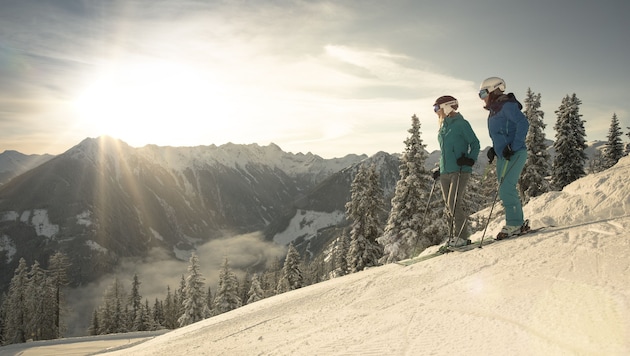 Skifahrer genießen den wunderebaren Ausblick von der Piste.
