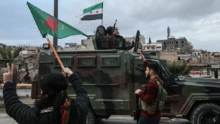 Eine kurdische Kämpferin schwenkt die Flagge der Frauenverteidigungseinheiten (YPJ) vor ...