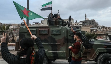 Eine kurdische Kämpferin schwenkt die Flagge der Frauenverteidigungseinheiten (YPJ) vor ...