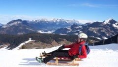 Der Wilde Kaiser (im Hintergrund) bildet einen Teil der Kulisse während der Rodelpartie in der ...