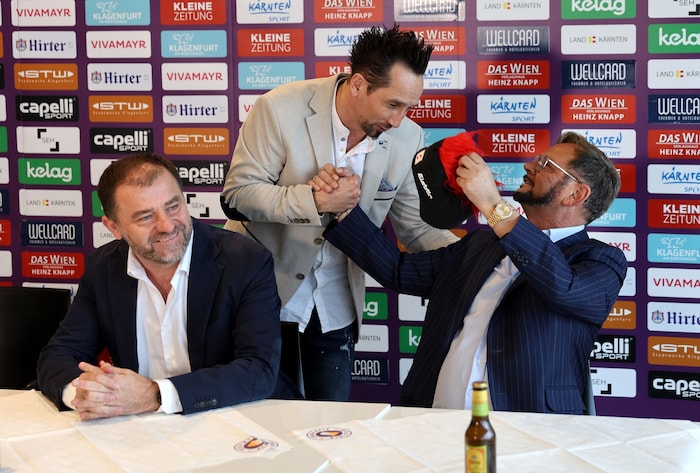 Dollinger übergibt Kaltenegger eine Haube, Karajica lächelt gequält.