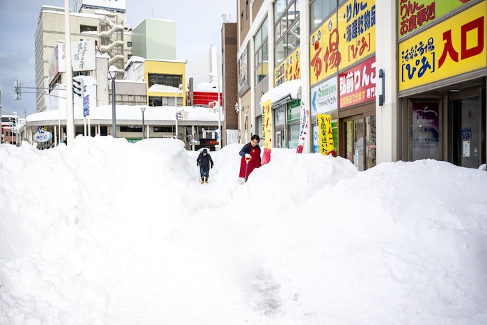 Ein Angestellter schaufelt am 30. Jänner in Aomori vor einem Geschäft den Schnee weg.