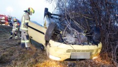 Der demolierte Pkw am Dach liegend neben der Autobahn 