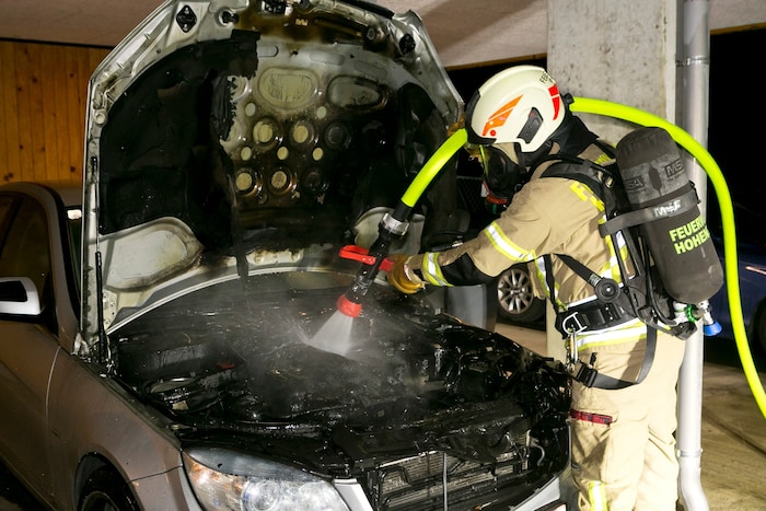 Ein Feuerwehrmann beim Löschen des Brandes im Motorraum des Wagens