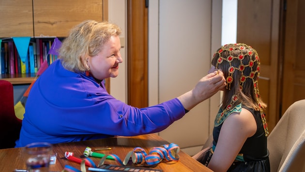 Ministerin Korinna Schumann hilft einem Mädchen bei den Faschingsvorbereitungen.