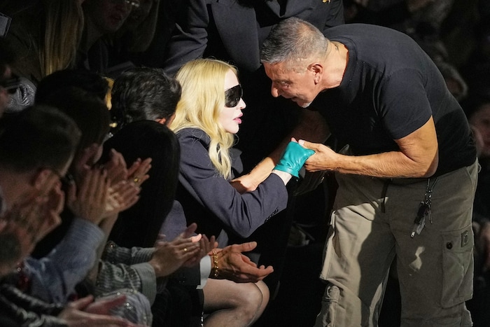 Mit schwarzer Sonnenbrille und türkisen Lederhandschuhen nahm Madonna in der Frontrow Platz.