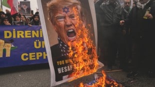 Proiranische Demonstranten verbrennen ein antisemitisches Porträt des US-Präsidenten.