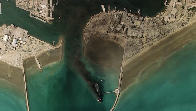 Smoke clouds and a destroyed ship in the port of Bandar Abbas on the Strait of Hormuz