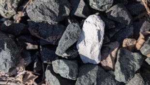 Ein weißer, asbesthaltiger Stein zwischen Schottersteinen