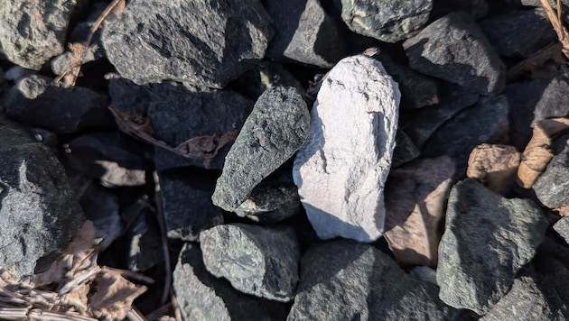 Ein weißer, asbesthaltiger Stein zwischen Schottersteinen