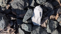 Ein weißer, asbesthaltiger Stein zwischen Schottersteinen