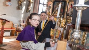 Armin Puschl beim Anzünden der Kerzen mit Laura, Ministrantin und Tochter, in Mieger 