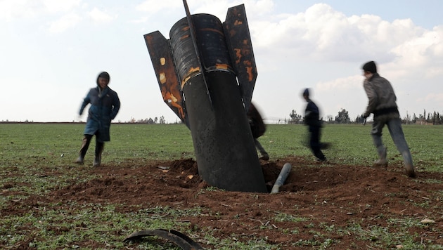 Children run around an unexploded Iranian rocket that landed in an open field on the outskirts ...