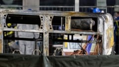 Brandermittler untersuchen die verkohlte Hülle eines Linienbusses, der in Brand geraten war. Es ...
