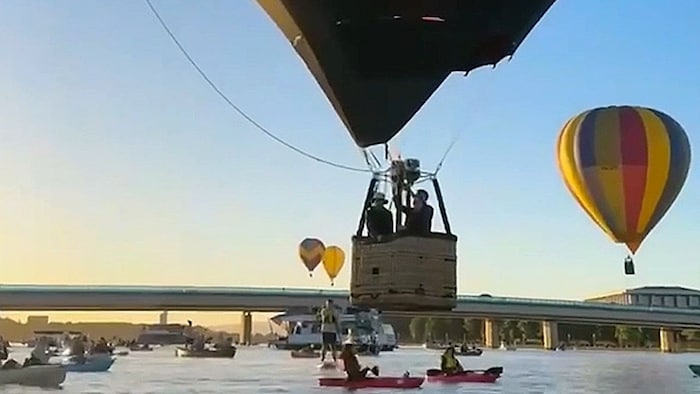 Die Heißluftballon-Piloten fliegen knapp über der Wasseroberfläche.