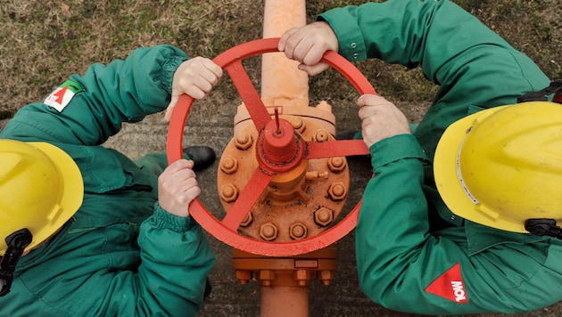 Arbeiter des ungarischen Öl- und Gasunternehmens MOL drehen an einem Gasventil und die ...