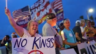 Eine Frau hält ein „No Kings“-Schild bei einer Pro-Demokratie-Demo vor dem Anwesen des ...