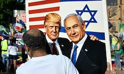 Ein Demonstrant hält eine Zeichnung von Trump und Netanyahu in die Höhe.