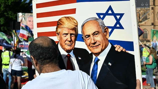 A protester holds up a drawing of Trump and Netanyahu.