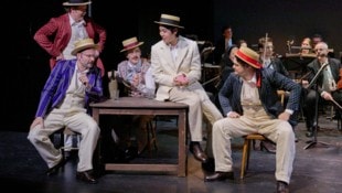 Schmetternde Männer in altmodischen Anzügen erzählen im Nest singend und sprechend das Leben von ...