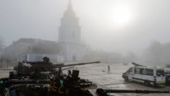 Jemand spaziert mit seinem Hund an zerstörten Militärfahrzeugen vorbei, während Nebel die ...