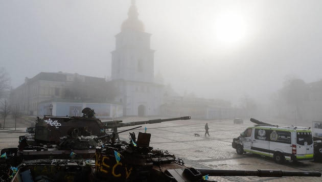 Jemand spaziert mit seinem Hund an zerstörten Militärfahrzeugen vorbei, während Nebel die ...