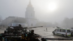 Jemand spaziert mit seinem Hund an zerstörten Militärfahrzeugen vorbei, während Nebel die ...