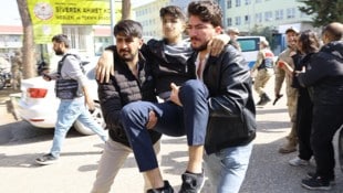 Ein verletzter Schüler wird von helfenden Händen weggebracht.